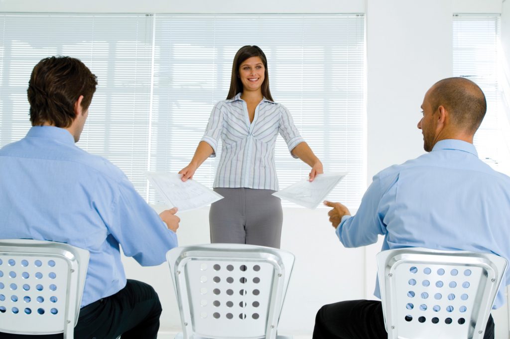 Businesswoman handing papers to businessmen